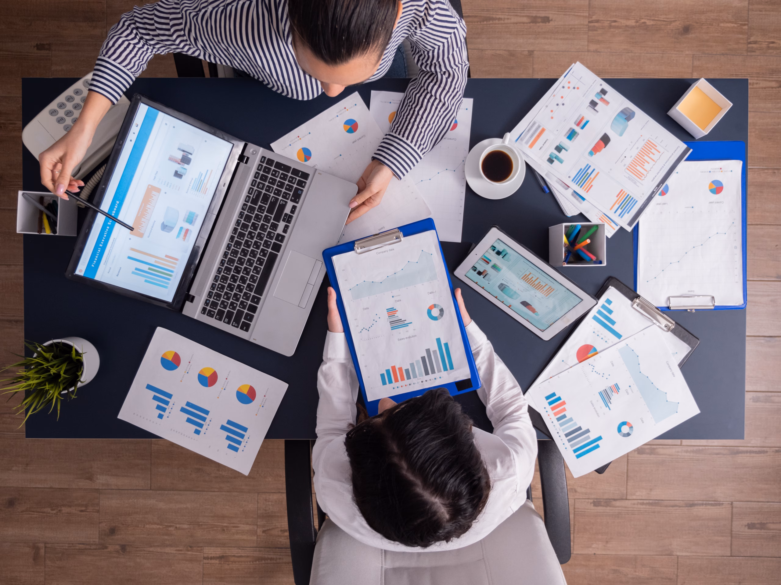 Top view of manager and employee doing teamwork Top viewTop view of manager and employee doing teamwork in business office , looking at charts on laptop display. Finance paperwork with charts at workplace. Discusing financial plan.